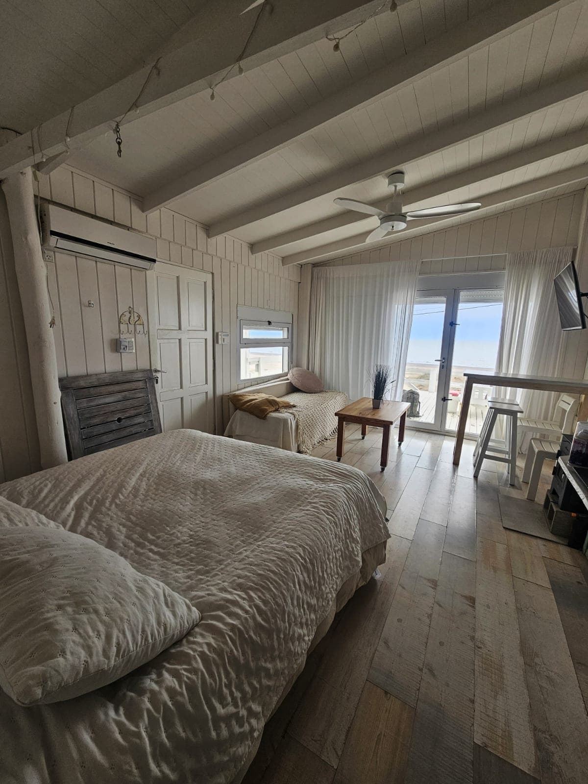 Living de Casa Gaviota con estufa, televisor y vista al mar